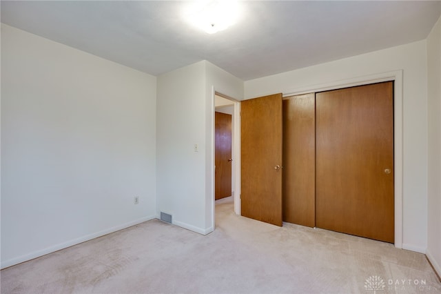 unfurnished bedroom with baseboards, a closet, visible vents, and light colored carpet