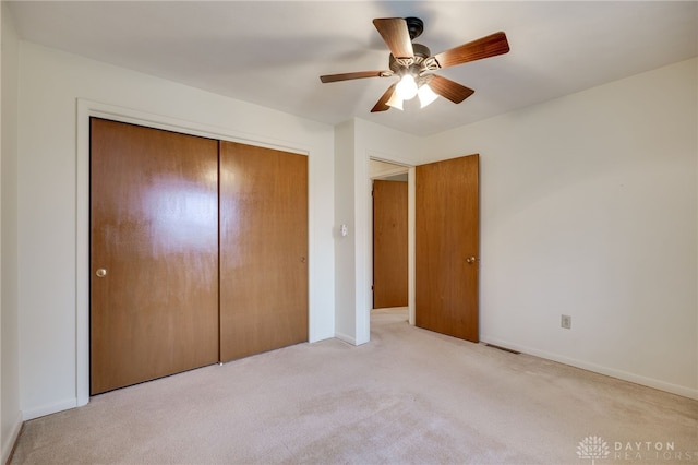 unfurnished bedroom featuring ceiling fan, baseboards, a closet, and light colored carpet