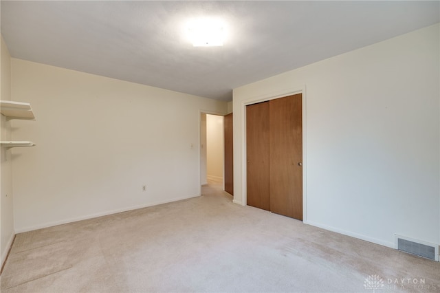 unfurnished bedroom with a closet, visible vents, light carpet, and baseboards