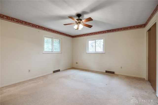 unfurnished room featuring visible vents, a wealth of natural light, and light colored carpet