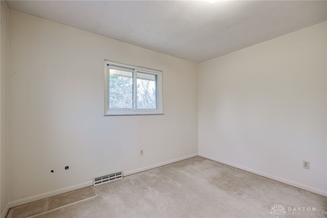 unfurnished room with light carpet, visible vents, and baseboards