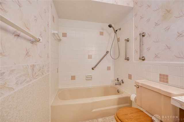 full bathroom with toilet, wallpapered walls, washtub / shower combination, and tile walls