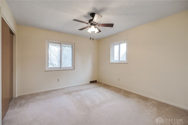 unfurnished bedroom featuring light carpet, a ceiling fan, baseboards, and a closet