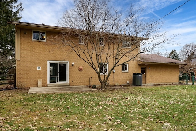 back of house with cooling unit, brick siding, a patio, and a lawn