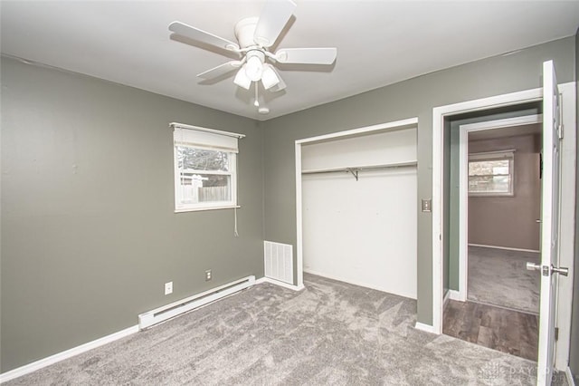 unfurnished bedroom with a baseboard radiator, carpet flooring, a closet, and multiple windows