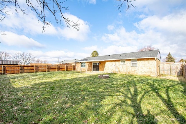 rear view of house with a yard and an outdoor fire pit