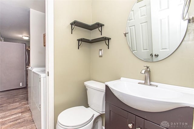 bathroom with vanity, hardwood / wood-style flooring, washer and clothes dryer, and toilet