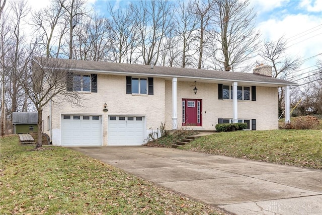 split foyer home featuring an attached garage, a chimney, a front lawn, and brick siding