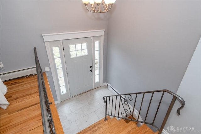 foyer entrance featuring a chandelier, baseboard heating, a baseboard radiator, and baseboards