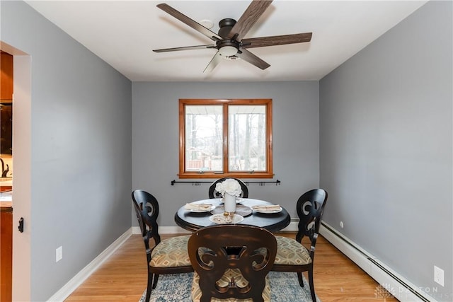 dining space with ceiling fan, a baseboard radiator, baseboards, and light wood-style flooring