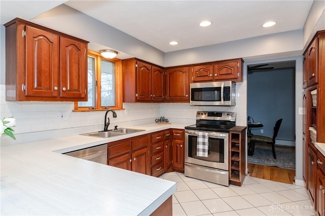 kitchen featuring light tile patterned floors, tasteful backsplash, stainless steel appliances, light countertops, and a sink