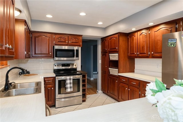 kitchen with light tile patterned floors, a sink, light countertops, appliances with stainless steel finishes, and decorative backsplash