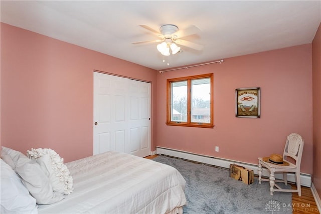 bedroom with baseboards, a ceiling fan, wood finished floors, baseboard heating, and a closet