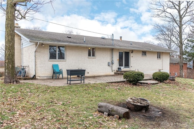 back of house featuring a fire pit, brick siding, a chimney, and a patio area