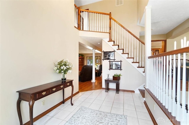 tiled foyer entrance featuring decorative columns and a high ceiling