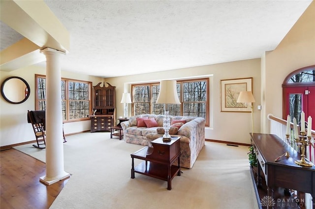 living room featuring ornate columns, light colored carpet, and a textured ceiling