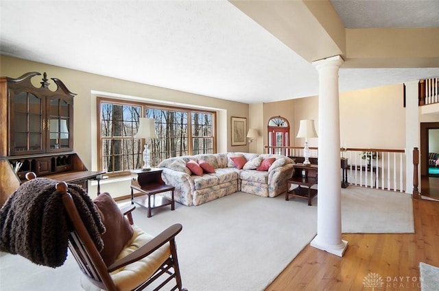 living room with decorative columns, a textured ceiling, and light hardwood / wood-style floors