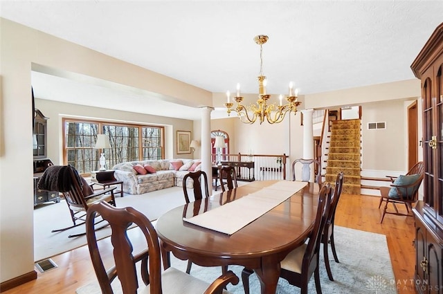 dining space with ornate columns, a chandelier, and light hardwood / wood-style floors