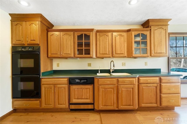 kitchen featuring double oven, dishwasher, sink, light wood-type flooring, and a textured ceiling