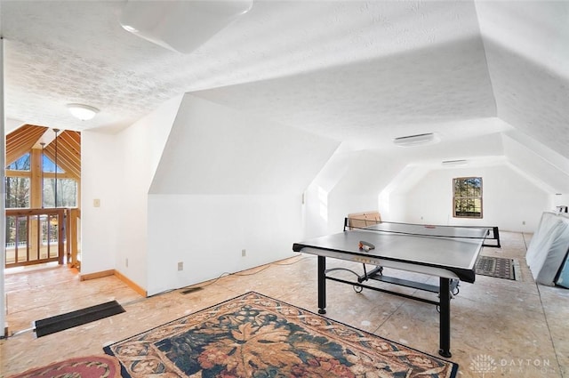 recreation room featuring lofted ceiling and a textured ceiling