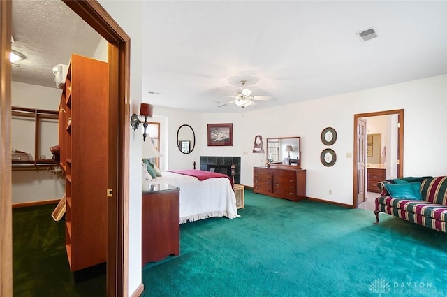 carpeted bedroom with ceiling fan, ensuite bathroom, a fireplace, and a spacious closet