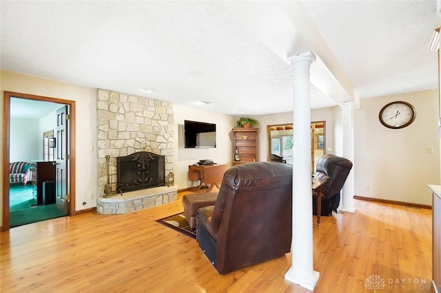 living room with a fireplace, light hardwood / wood-style floors, and ornate columns