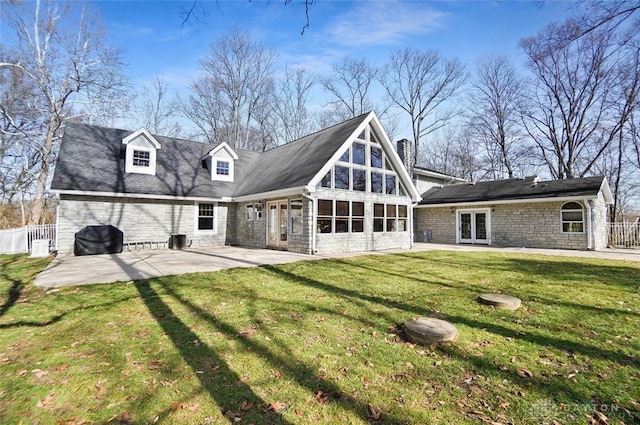 back of property with french doors, a sunroom, a patio, and a lawn