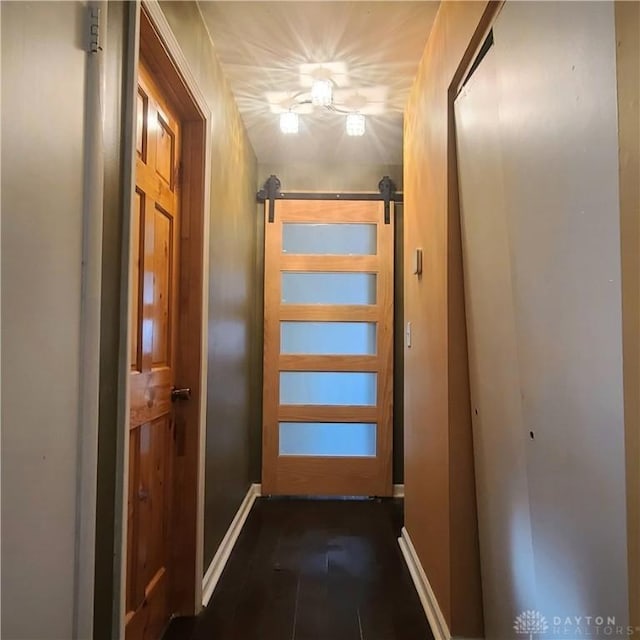 hall featuring a barn door and dark tile patterned flooring