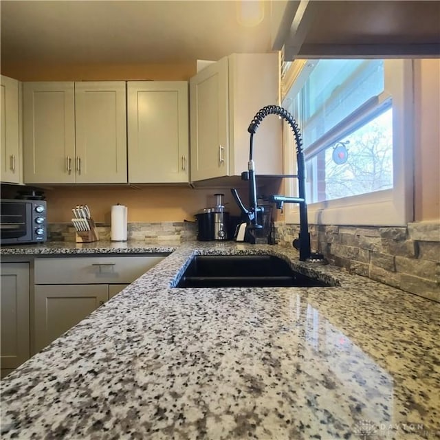 kitchen featuring sink, white cabinets, and light stone counters