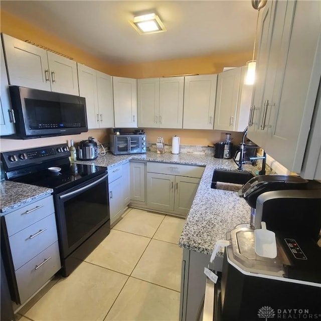 kitchen with light tile patterned floors, sink, black electric range, and white cabinets