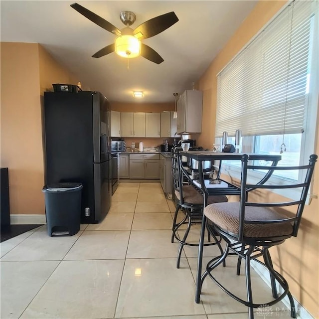 kitchen with range, light brown cabinets, light tile patterned floors, stainless steel fridge, and ceiling fan