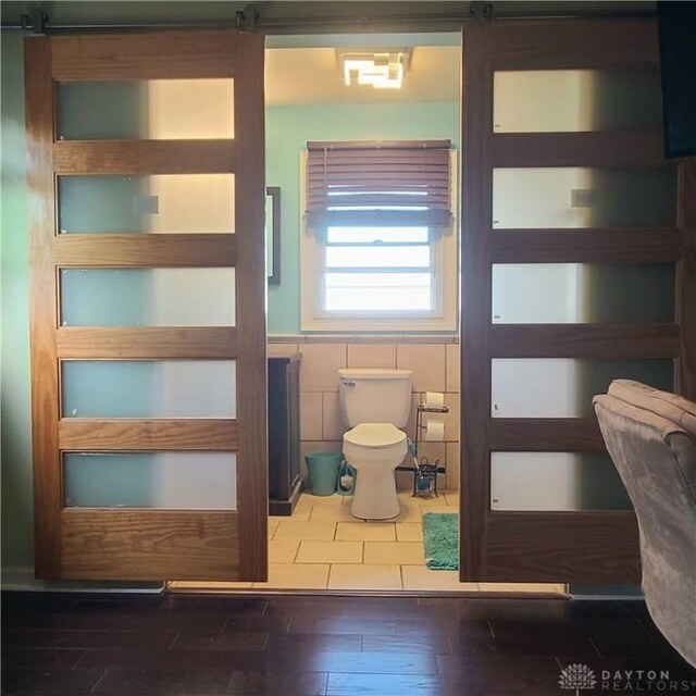 bathroom featuring tile walls, wood-type flooring, and toilet