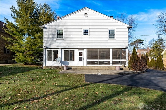 rear view of house featuring a sunroom, a yard, and a patio area