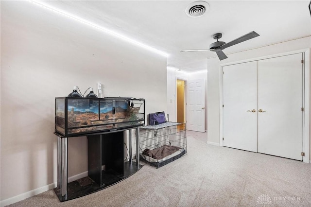 interior space with light carpet, ceiling fan, and a closet