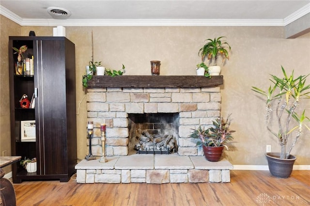 interior details with ornamental molding, wood-type flooring, and a stone fireplace