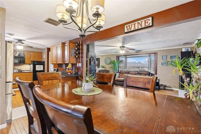 dining room featuring crown molding, ceiling fan with notable chandelier, and light hardwood / wood-style floors