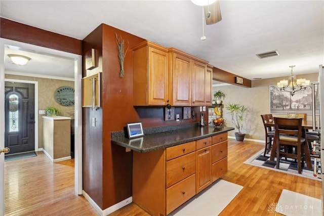 kitchen featuring pendant lighting, a notable chandelier, light hardwood / wood-style floors, and dark stone counters