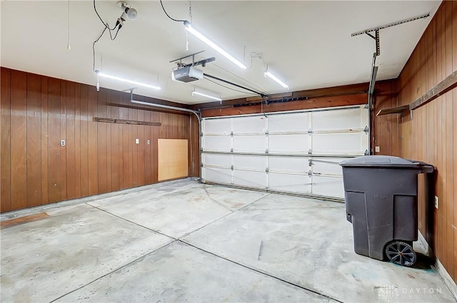 garage featuring a garage door opener and wooden walls