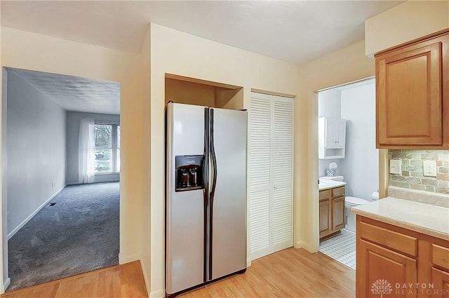 kitchen with tasteful backsplash, light hardwood / wood-style flooring, and stainless steel fridge with ice dispenser