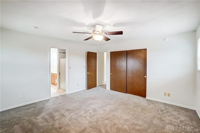 unfurnished bedroom featuring ceiling fan, light colored carpet, ensuite bathroom, and a closet