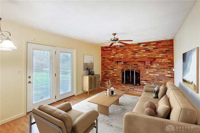 living room featuring ceiling fan, light hardwood / wood-style floors, and a brick fireplace