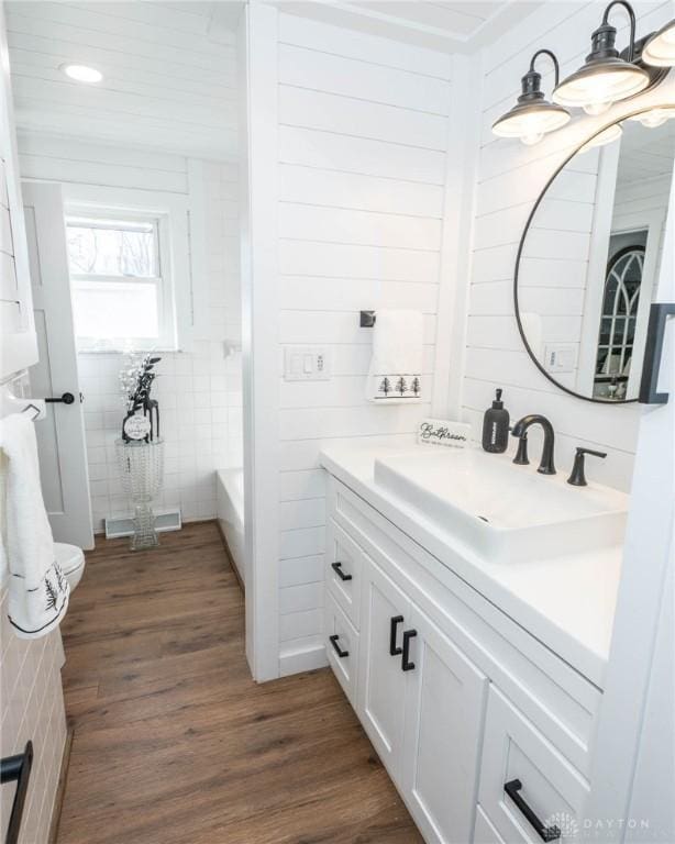 330 W Spring St, Eaton, OH 45320 - bathroom featuring vanity, wood finished floors, a tub to relax in, recessed lighting, and tile walls