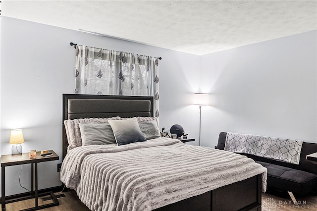 bedroom with dark hardwood / wood-style floors and a textured ceiling