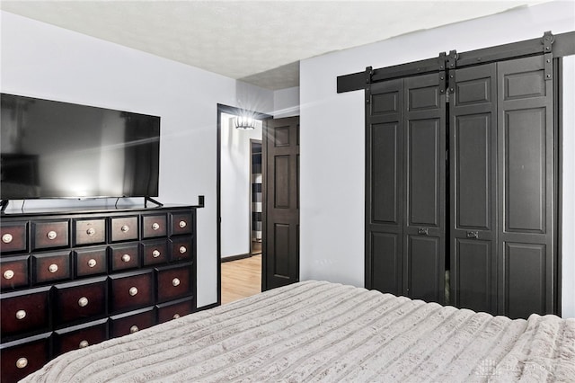 bedroom with a barn door, a closet, and light wood-type flooring