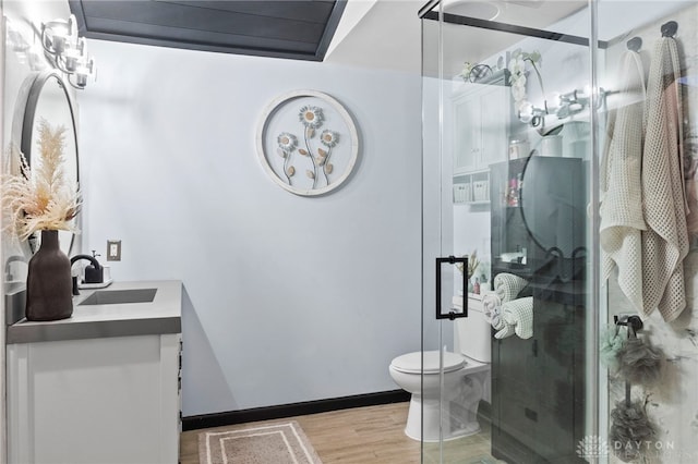 bathroom with vanity, hardwood / wood-style flooring, a shower with door, and toilet