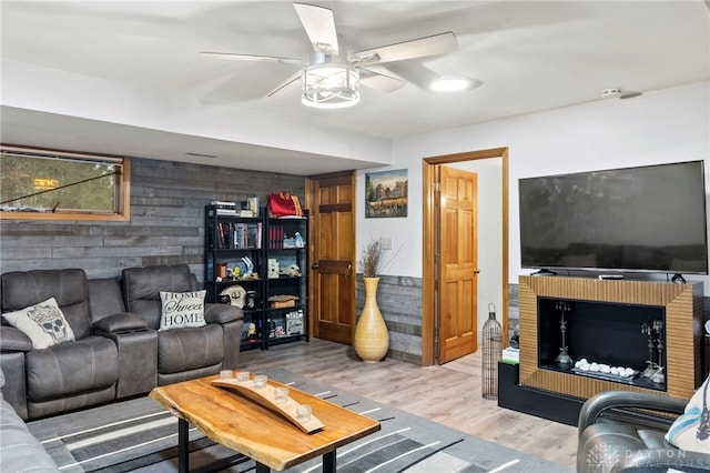 living room featuring a fireplace, light hardwood / wood-style flooring, and ceiling fan