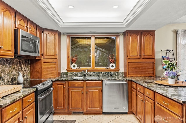 kitchen featuring appliances with stainless steel finishes, a raised ceiling, sink, and dark stone countertops