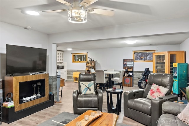 living room featuring a brick fireplace, light hardwood / wood-style floors, and ceiling fan