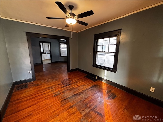 spare room featuring dark wood-type flooring, ceiling fan, and ornamental molding