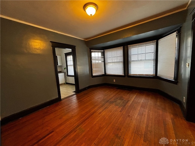 spare room featuring wood-type flooring and ornamental molding